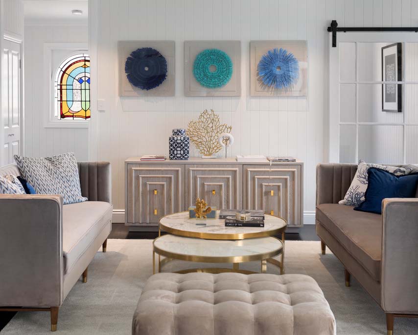 A modern seating area with a luxury coffee table and side unit styled with accessories and framed art.