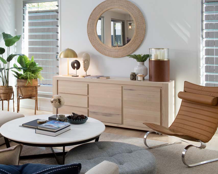 A seating area with a coffee table and side unit styled with accessories and plants.