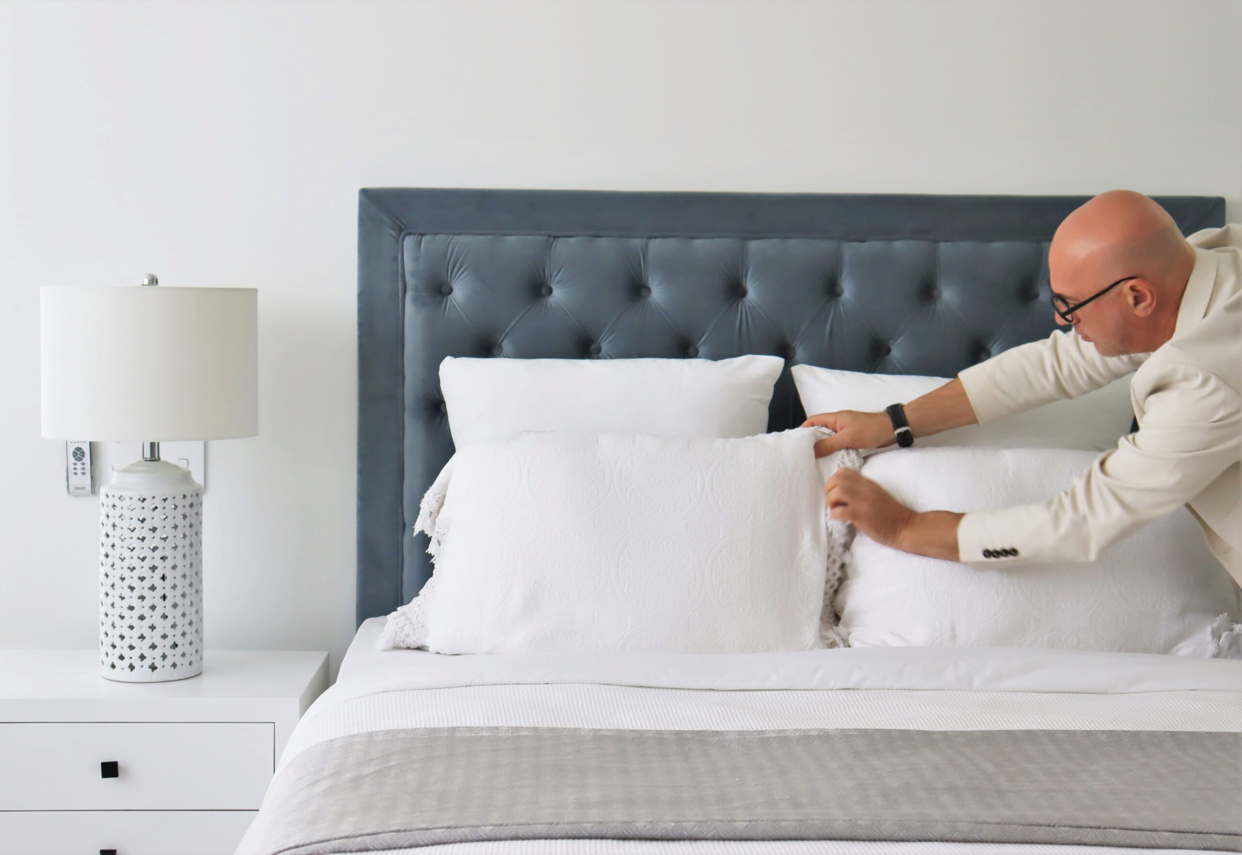 An expert stylist arranging the pillows on a bed ready for sale