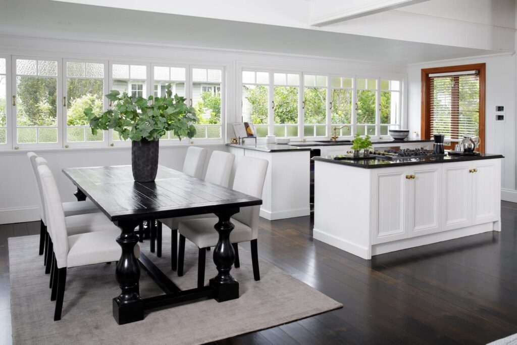 A modern open plant kitchen dining area with a white and dark wood aesthetic.