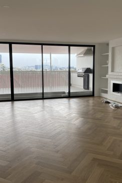 Empty living room with a wooden herringbone style floor
