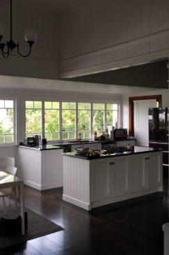 Photo of a white kitchen and dining area with dark wood floors