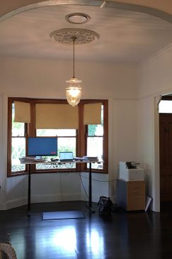 Before a renovation photo showing a front room and entry way with dark wood floors