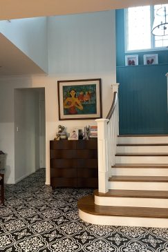 Patterned floor tiles in a hallway with staircase and turquoise walls