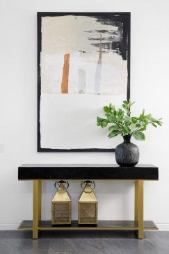 A side unit styled with a vase, lanterns and a large abstract piece of wall art