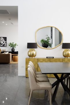 A dining area with gold sideboard styled with lamps and gold framed mirror