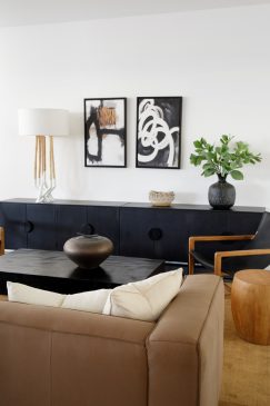 A sitting area in a light, modern home with a dark side unit and wall art