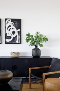 A sitting area in a light, modern home with a dark side unit and wall art