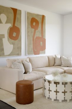 A modern neutral living area with large wall art and a unique coffee table.