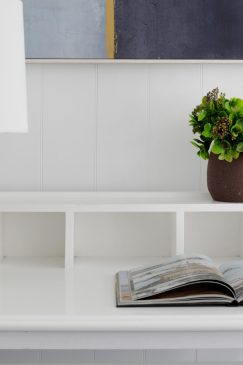 A close up of a desk with a feature lamp, plant pot and an open book