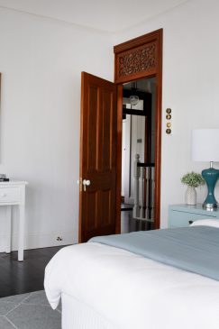 A calm coloured bedroom with large floral wall art and turquoise lamp