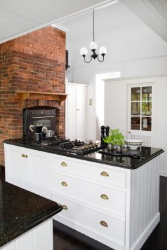 A white and black aesthetic kitchen with an exposed brick feature wall.