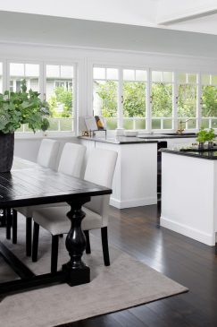 A modern open plant kitchen dining area with a white and dark wood aesthetic.