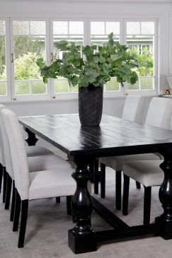 A dark wood dining table with white chairs
