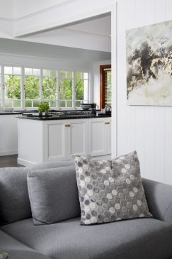 Comfy grey sofa in an open plan living room with a view of the white kitchen behind