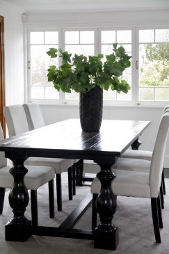 White dining room with a dark wood table and comfy looking chairs