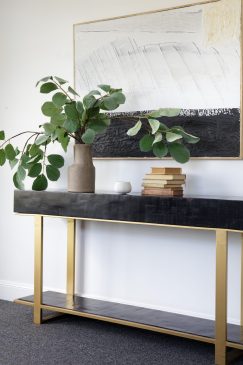 Black and gold side unit with a large plant and art piece