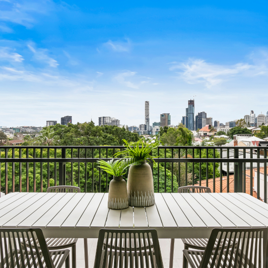 Blue skies over Brisbane city. A view from a balcony with a dining table and chairs